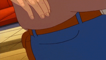 A man in a brown shirt, orange hat, and sunglasses pulls sand out of his jeans pocket and throws it into another man's face while shouting, "Pocket sand!"