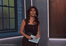 a woman in a black dress reacting and saying "What?!"