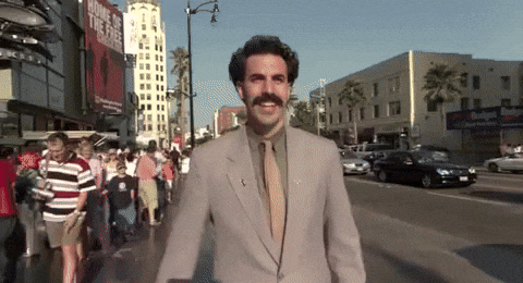 An excited man wearing a gray suit while walking through a city.