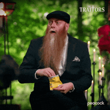 A man with a long beard eating chips out of a bag and watching intently