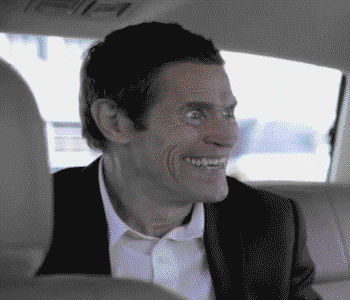 Zooming in on a white man (Willem Dafoe) with short hair and a crazd look in his eyes.