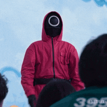 a man in a red hoodie standing in front of a crowd