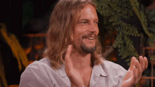 a man with long hair claps