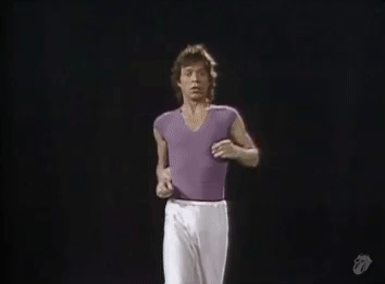 A man in a light purple shirt and white pants dancing ridiculously.
