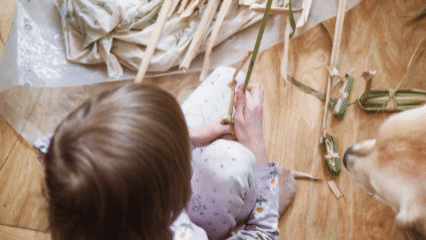 A small child making cattail ducks and floating them in a puddle