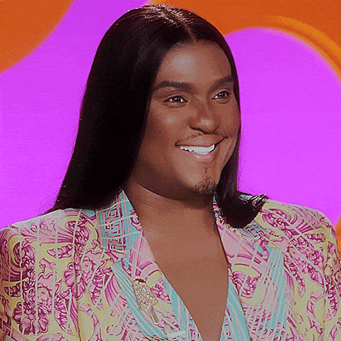 a man in a colorful suit sticks his tongue out quickly and laughs
