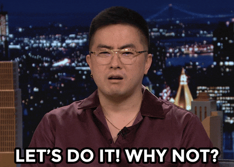 An Asian man with short black hair (Bowen Yang) in glasses and a maroon collared shirt.