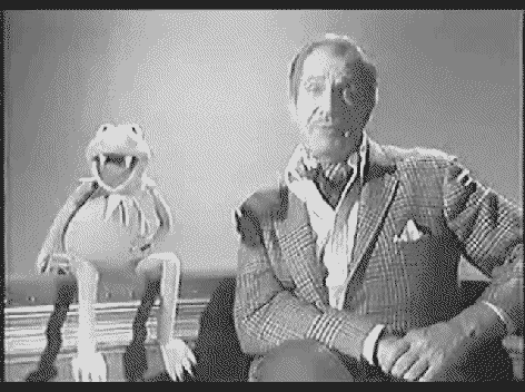 Kermit the Frog with vampire teeth strtles Vincent Price by biting him on the neck.