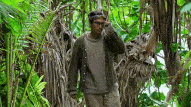 A person walking through a jungle shaking their head and touching their hair