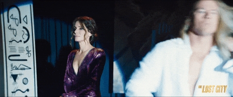 GIF from The Lost City: Channing Tatum in a long blonde wig sliding into frame with a flourish