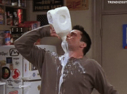 a man drinking milk from a jug and pouring it down his face and body