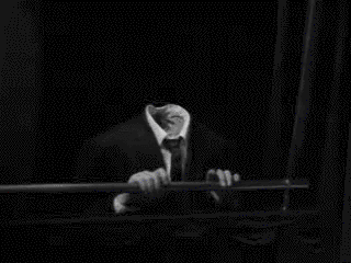 A black and white film clip showing a headless person drumming their fingers on a ledge