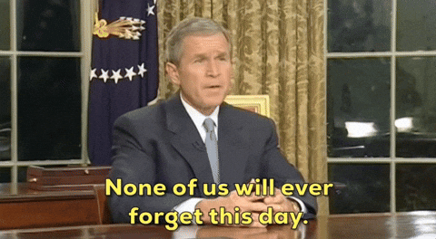 George W. Bush sitting at his desk saying, "None of us will ever forget this day."