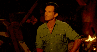 a man in a green shirt sitting in front of a fire saying "Wow"