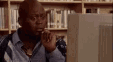 Tituss Burgess looking at a computer monitor and recoiling in horror