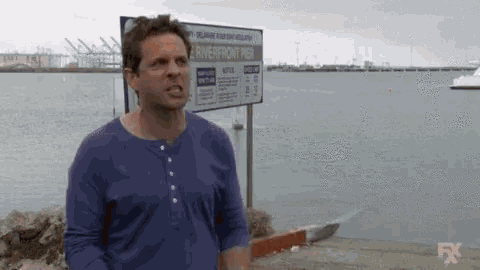 a man standing next to a body of water screaming I AM THE GOLDEN GOD, and the image turns to fire