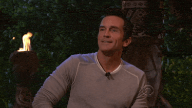 a man sitting in front of a fire throwing a card away