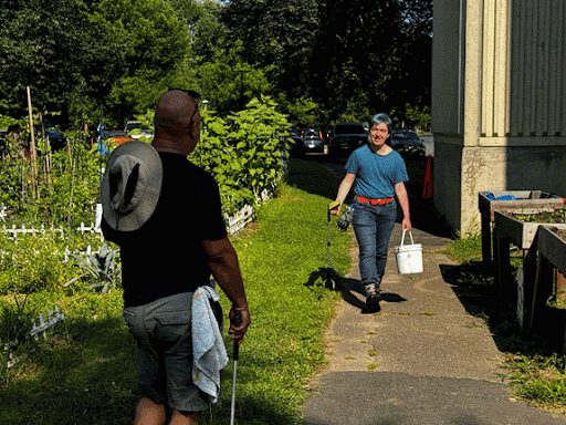 Succession of images of Ace Tayloe walking up and posing for the camera with Councilor Garrick Perry, both carrying outdoor clean-up supplies, outside of Salvo House
