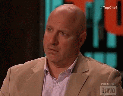 a bald man in a tan suit looking bewildered