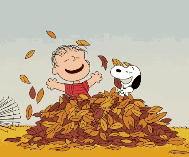 Linus and Snoopy in a pile of fall leaves, throwing them around