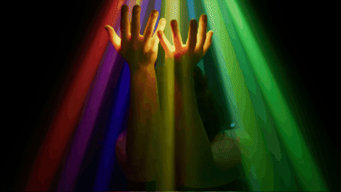 person dances underneath projected rainbow